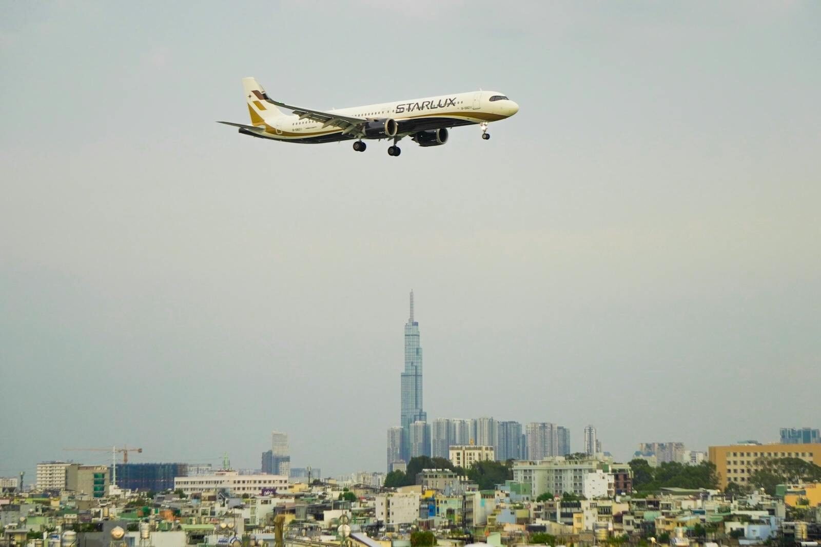 Airplane flying over city skyline - flight booking tips and hacks to save money on airfare