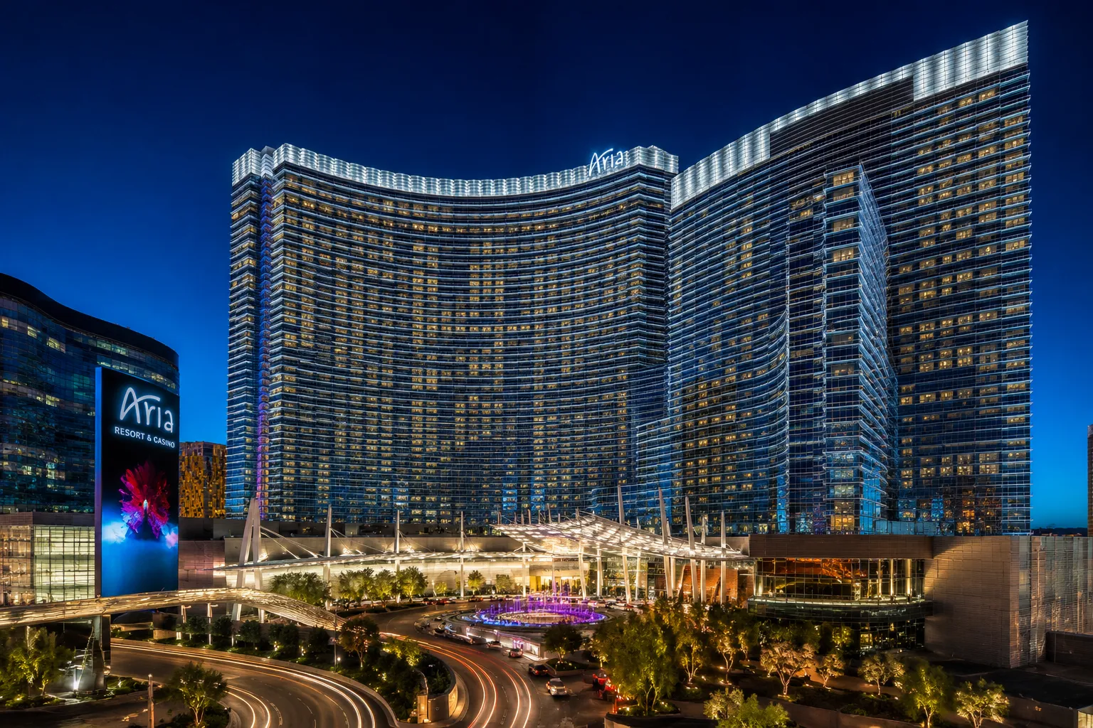 The modern curvilinear glass skyscraper facade of Aria Las Vegas resort illuminated at night