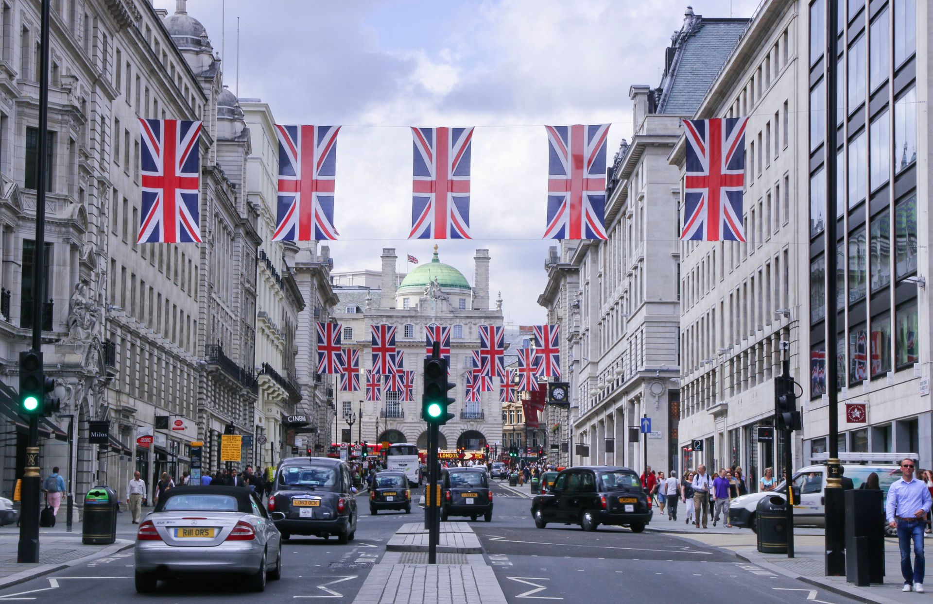 A bustling street corner in central London with historic buildings and pedestrians walking near premium accommodation options highlighting cheap hotels in central london