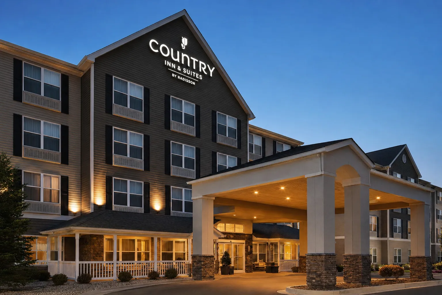 The modern exterior building and main entrance canopy of Country Inn and Suites by Radisson during twilight