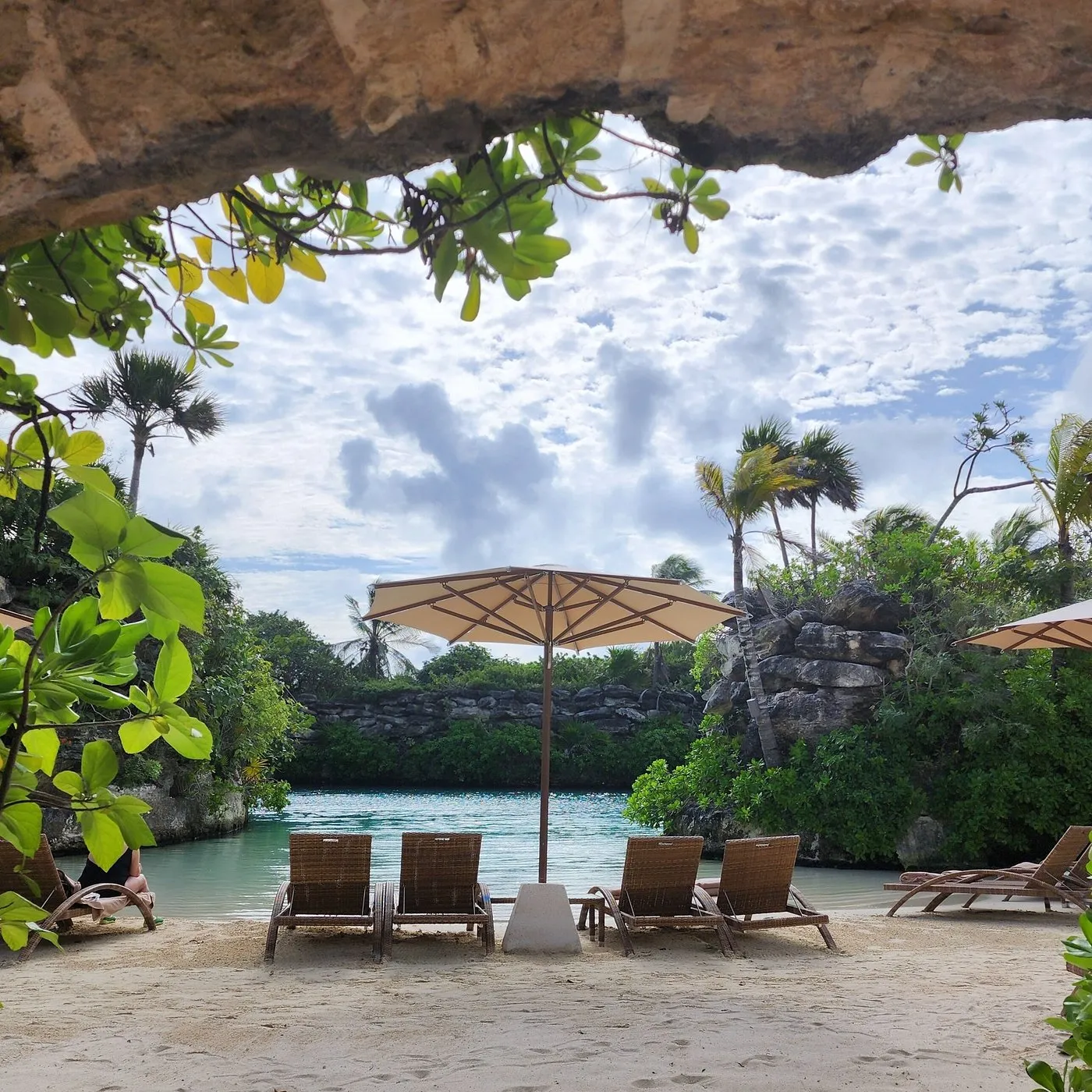 Cozy lounge chairs under umbrellas on the private beach cove at Xcaret Hotel